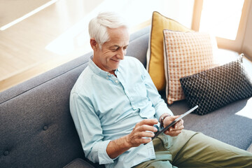 Sticker - Senior man, technology and retirement in home for typing email, communication and reading online news. Elderly person, tablet and relax on sofa in lounge for bills payment, webinar or streaming movie