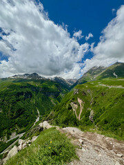 Panoramic view of lush green Caucasus mountain peaks with cloudy blue sky