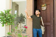 © AntonioDiaz - Hispanic man with a messenger bag waving and saying hello to his neighbor as he leaves his house