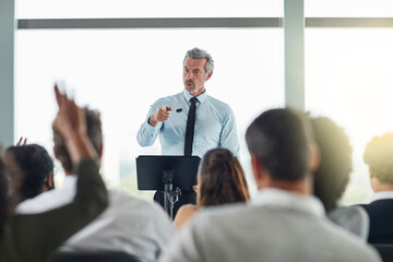 Poster - Podium, mature man and question in seminar, speaker and audience in event, training and presentation in boardroom. Workshop, speech and talking in conference, entrepreneurship and masterclass