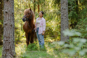 Wall Mural - Woman with Icenlandic horse in forest with sunset on behind