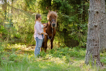 Wall Mural - Woman with Icenlandic horse in forest with sunset on behind