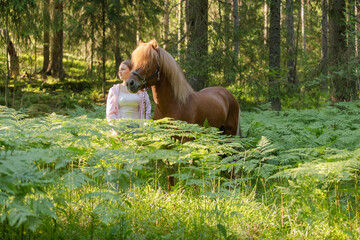 Wall Mural - Woman with Icelandic horse middle of ferns during the sunset