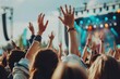 © mariodelavega - A cheerful crowd at an outdoor music festival during the day, with people dancing, singing along, and waving their hands in the air.