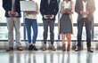 © peopleimages.com - Group of people, technology and waiting room as candidates for job opportunity, hiring and onboarding assessment. Legs, staff and employees as team in modern office, recruitment and human resources