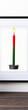 © ahlemrafika - A single red and green candle burning brightly in a black holder against a white background.