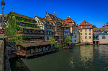 Poster - Ornate traditional half timbered houses with blooming flowers along the canals in the picturesque Petite France district of Strasbourg, Alsace, France