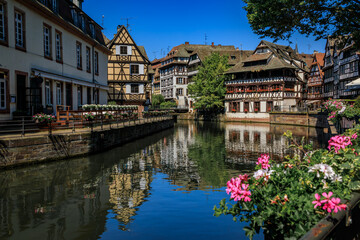 Poster - Ornate traditional half timbered houses with blooming flowers along the canals in the picturesque Petite France district of Strasbourg, Alsace, France