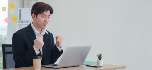 Business man manager employee asian one person sitting on desk look smile happy enjoy and determined expression hand holding laptop notebook ready for working online sale inside room office company