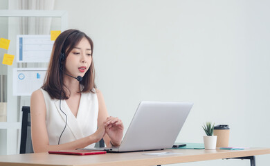 Wall Mural - Employee woman girl asian one person smile happy enjoy sitting chair on desk looking talk telephone and hand holding notebook laptop ready for business service call center working job in room office