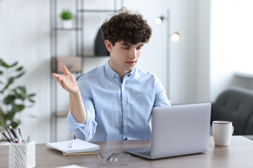 Wall Mural - Teenager having video chat via laptop at table indoors. Remote work