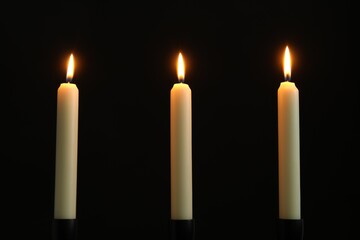 Wall Mural - Many burning church candles on black background