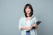 © Jirawatfoto - young enterpriser manager, asian working woman holding tablet and smiling, standing over green background