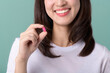 © Jirawatfoto - Vitamin supplements. Healthy Asian woman holding pills or vitamin supplements and smiling happily isolated on green background.