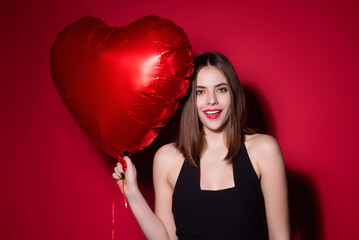 beautiful girl with heart shape air balloon on studio isolated background. woman on valentines day. 