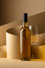 Wall Mural - Bottle and glass of white wine on a beige background.