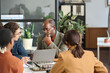 © Mediaphotos - Diverse group of business people sitting at meeting table together and brainstorming ideas with focus on senior man listening to young colleague