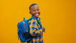 © Antto-AI - A cheerful black young boy with a colorful plaid shirt and blue backpack smiles against a vibrant yellow background with copy space, ready for school.