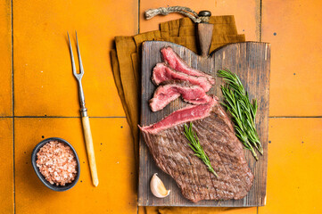 Wall Mural - BBQ dry aged wagyu Flank Steak on a cutting board. Orange background. Top view