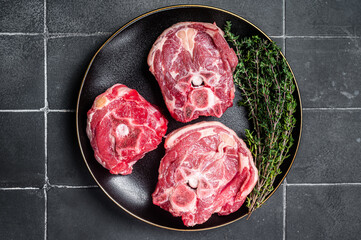 Canvas Print - Raw Lamb Gerdan, lamb neck chops on a plate with herbs. Black background. Top view