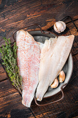 Wall Mural - Raw red perch fillet, redfish fish meat in a steel tray. Wooden background. Top view