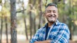 © ifoto - portrait of smiling middle aged Hispanic man standing in the park with arms crossed