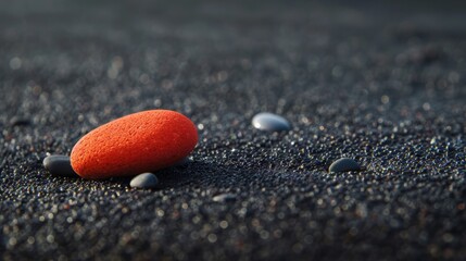 Sticker - Vibrant orange stone on a sparkling black sand beach