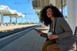 © DusanJelicic - Young woman sits at the train station, coffee in one hand and smart phone in the other, a picture of urban grace.