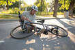 © Mihail - man wearing a helmet sits on the asphalt of a city street, his leg injured, after a bicycle crash