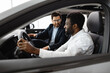 © Sofiia Shunkina - Professional interaction in modern automobile showcasing comfort, trust, and salesmanship. Caucasian car dealer sit inside vehicle with African American buyer discussing car features.