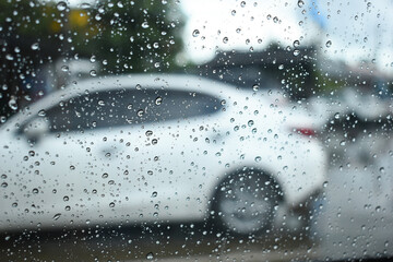 Wall Mural - water drop on mirror in defocused car parking background