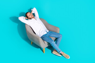 Poster - Full length top view photo of cheerful positive guy dressed white shirt relaxing arms behind head emtpy space isolated turquoise color background