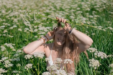 Young woman posing in a field of white wildflowers on a sunny day