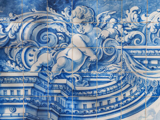 Traditional Portuguese, glazed ceramic tiles on building wall in the street of Oeiras. Azulejos white, blue ornate pattern, for design, backdrop. Decorative painted tiles, religious theme with angels.