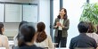 © Iryna - A Japanese businesswoman delivering a seminar on economics, engaging with colleagues.