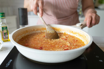 Wall Mural - Homemade food. Woman preparing a fresh cooked risotto with tomatoes in the kitchen