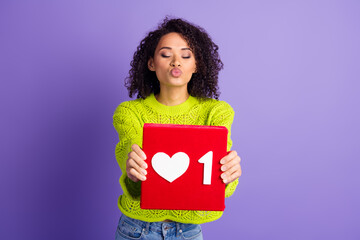 Wall Mural - Photo of young wavy haired kissing girl in green pullover holding red like button dating network isolated on violet color background