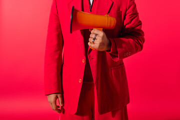 Wall Mural - Handsome young Indian man in red suit holding a megaphone.