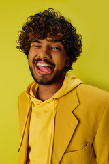 Wall Mural - Handsome young Indian man with curly hair posing in a vibrant yellow jacket.