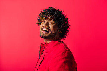 Wall Mural - A close-up of a handsome Indian man wearing a red shirt, posing against a vivid backdrop.