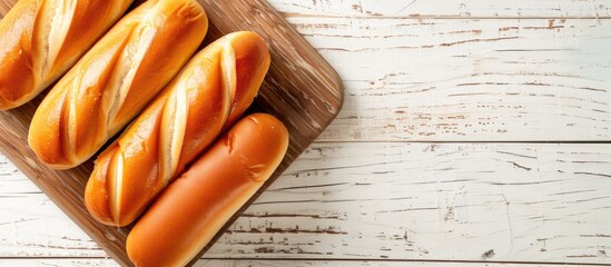 Canvas Print - Overhead view of hot dog buns on a rustic wooden board with a white wooden background, depicted in a flat lay style from above, offering ample copy space image.