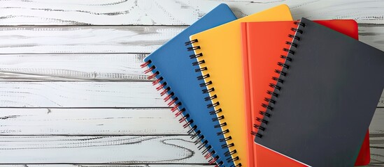 Poster - Notebooks arranged on a white wooden surface with ample copy space image.