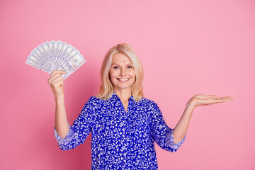 Wall Mural - Photo of pretty aged lady hold cash empty space wear blue shirt isolated on pink color background