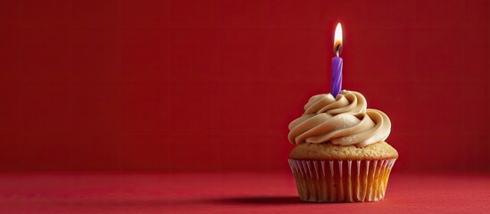 Poster - A caramel cupcake topped with a lone purple candle displayed against a red background, providing ample copy space in the image.