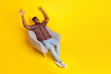 Wall Mural - Full body portrait of nice young man sit chair look empty space wear shirt isolated on yellow color background