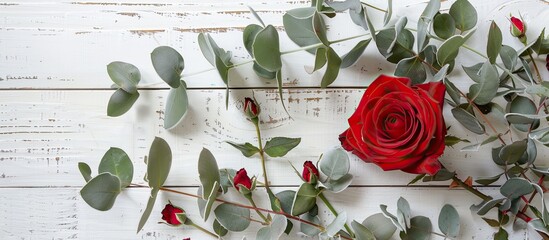 Aufkleber - Top-down image of red rose and flocked eucalyptus branches on a white wooden surface, creating a festive composition ideal for Christmas and New Year, with a winter theme, offering copy space.