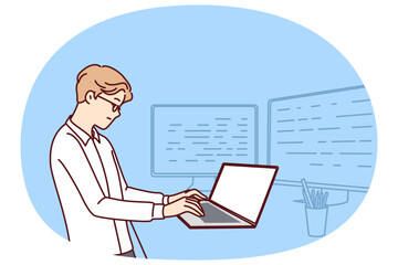Man software developer is standing at table with laptop and monitors creating server applications. Dispatcher guy works as it analyst using software to monitor load on company computer systems.