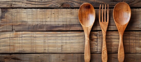 Aufkleber - Wooden spoon and fork displayed on a brown wooden background with copy space, viewed from above.
