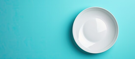 Leinwandbilder - Top view of an empty white plate on a blue background table with copy space image.