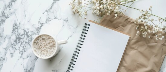 Poster - Top-down view of a blank notebook page on a white marble table with a frame composition perfect for copy space image.